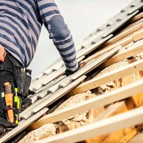 Couvreur posant des tuiles sur une toiture à Lançon